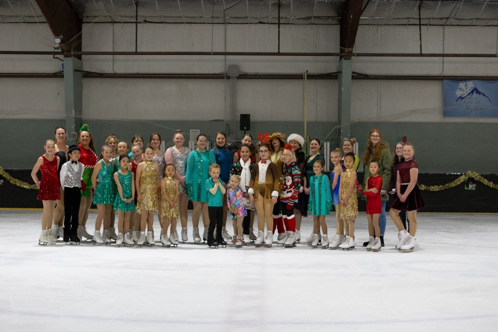 Group of smiling ice skaters dressed in holiday clothes.
